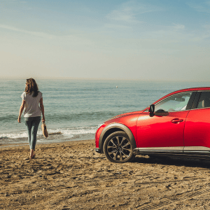 imagen de mujer y coche mazda en la playa